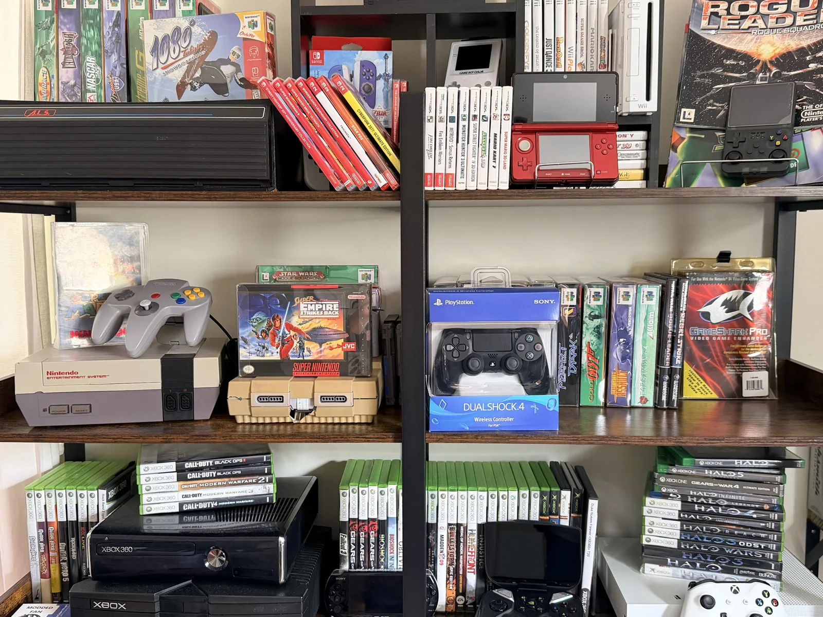 A collector's shelves of boxed Nintendo 64, Super Nintendo, 3DS, Switch and Xbox games alongside NES, SNES, Xbox 360 and original Xbox consoles
