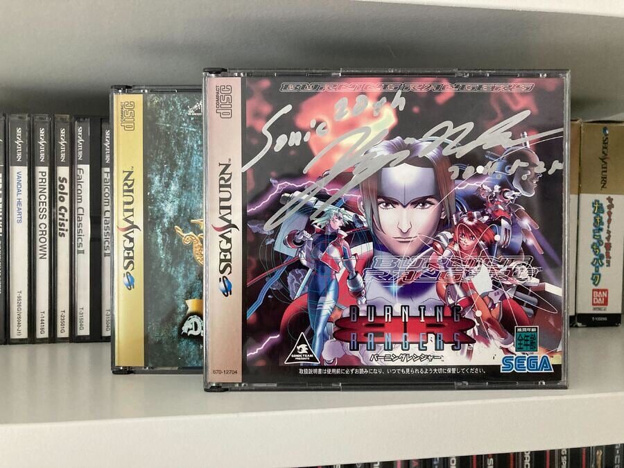 A Sega Saturn game on a shelf with sun-faded spines beside it — UV light damage to game cases
